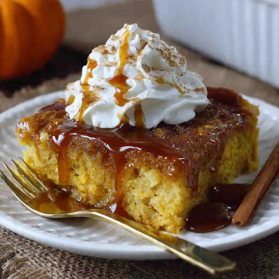 Pumpkin cake slice with whipped cream and cinnamon under caramel drizzle.