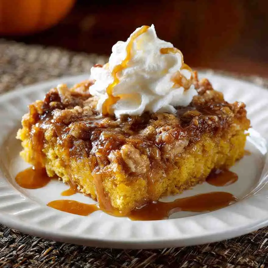 Pumpkin dump cake topped with crunchy streusel and caramel sauce.